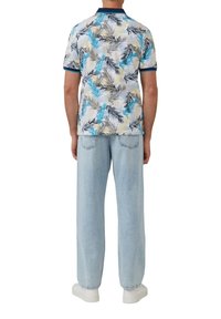 Koszulka polo z krótkim rękawem z wielokolorowym wzorem liści, z granatowym kołnierzykiem i mankietami, połączona z jasnoniebieskimi szerokimi spodniami dżinsowymi.