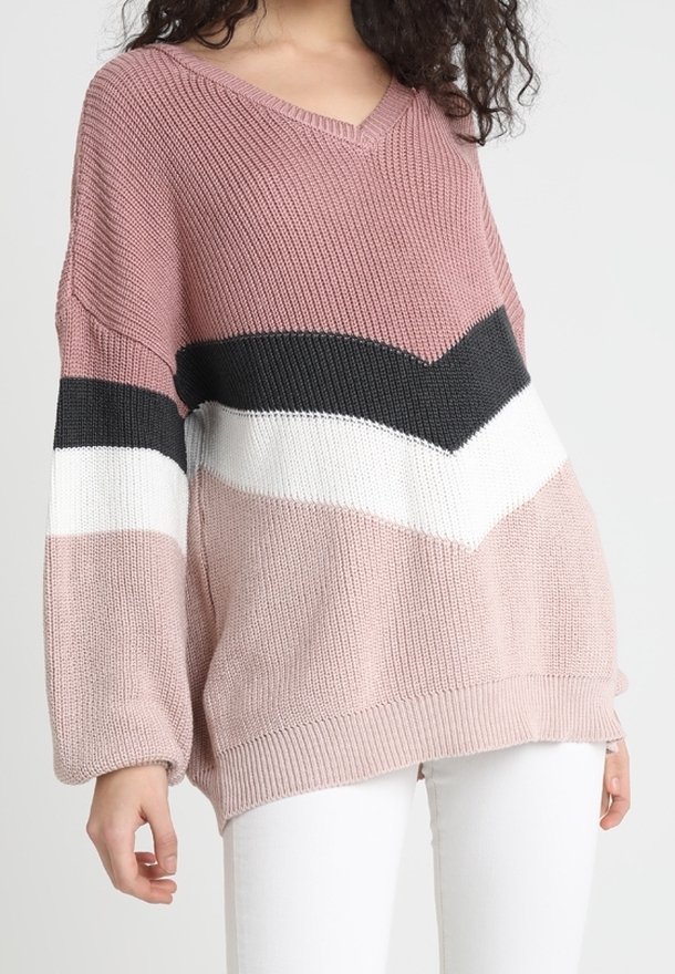 Oversized Strickpullover in Pink und Creme mit schwarzen und weißen Chevron-Streifen, ausgestattet mit V-Ausschnitt sowie gerippten Bündchen und Saum.