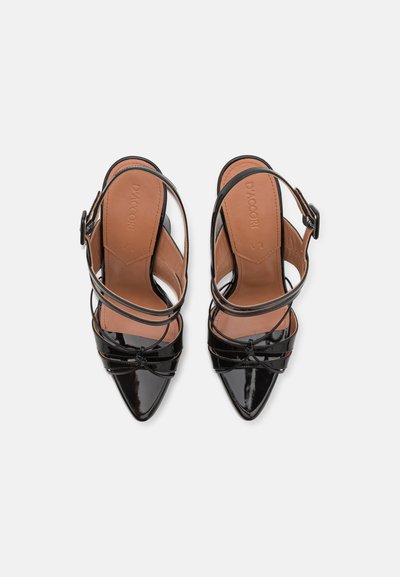 Decollete slingback in vernice nera con punta affilata, cinturini incrociati e soletta color beige. Chiusura con fibbia alla caviglia.