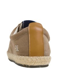 Scarpa slip-on in suede di colore marrone con un accento in pelle marrone sul tacco. Presenta una suola in corda di juta e dettagli ricamati.