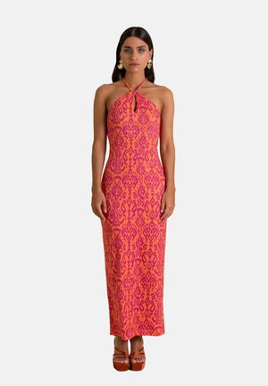 Robe maxi rose colorée avec un col halter et un motif violet complexe ; présente une coupe ajustée et une texture subtile. Sandales à plateformes empilées.