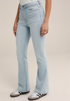 Light blue flared jeans made of denim, featuring a high waist, subtle stitching, and a smooth finish. Paired with grey and black sneakers.