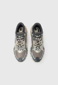 Hallide ja mustade spordijalatsite paar, millel on mustriga paelad, võrgu- ja sünteetiline pealmine osa, nähtud ülalt valgel taustal.