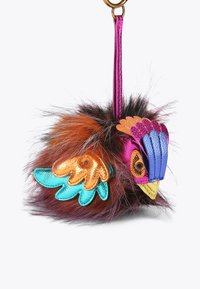 Portachiavi a forma di uccello in peluche dai colori vivaci: arancione, rosa, teal e oro. Presenta una texture in pelliccia sintetica, accenti metallici e un design morbido e arrotondato.