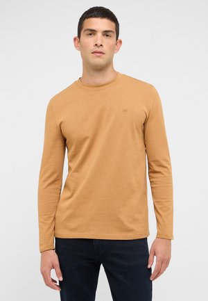 Langarmshirt mit Rundhalsausschnitt aus senffarbenem Stoff, mit schmaler Passform und kleinem gesticktem Logo auf der Brust. Glatte Textur, minimalistisches Design.
