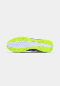 Hardloopschoenen met een fel geel-groene rubberen buitenzool, paarse accenten, een textuur op het oppervlak en een witte tussenzool met een gemusterde loopvlak.