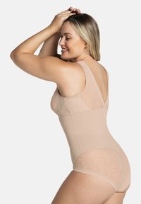 Naaktkleurig bodysuit met brede bandjes, voorzien van textuur-meshpanelen en een contoureerontwerp. Glad, rekbaar materiaal met een getailleerde pasvorm.
