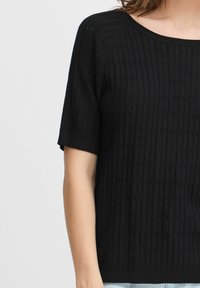 Sort strikket kortærmet sweater har vertikal ribstrik og subtile teksturdetaljer, med en bred halsudskæring og løs pasform.