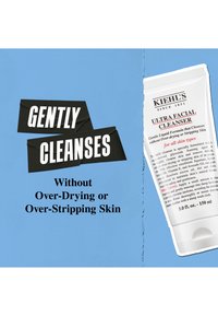 Kiehl's Ultra Facial Cleanser i en hvit tube, 150 ml, med svart tekst, som hevder skånsom rensing uten å tørke ut, mot en blå bakgrunn.