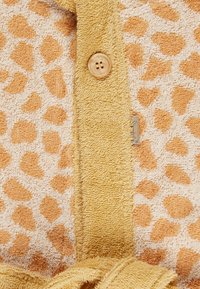 Tessuto con motivo leopardato in beige e arancione, con una texture morbida, caratterizzato da una patta con bottoni in spugna gialla e una cravatta coordinata.