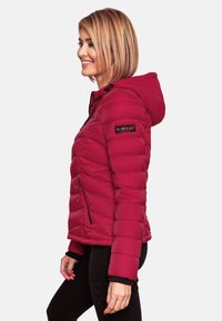 Red puffer jacket with a detachable hood, zippered pockets, and horizontal quilted pattern. Features a logo on the left sleeve.