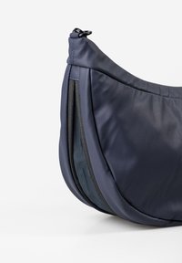Navyblaue Schultertasche aus glattem, strapazierfähigem Material; hat eine geschwungene Form und eine Reißverschlusstasche mit schwarzem Netzfutter.