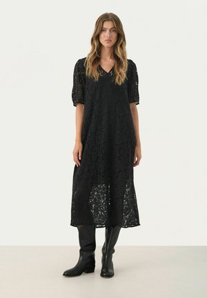 Black lace midi dress with short puff sleeves, featuring a V-neckline and a sheer texture, paired with knee-high black leather boots.