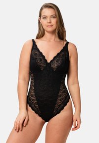 Svart spetstrosor med scallopade kanter, djup halsringning och justerbara remmar. Genomskinliga lakdetaljer på sidorna ger textur.