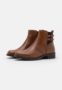 Brązowe skórzane botki za kostkę o gładkim wykończeniu, z elastycznymi bocznymi panelami i podwójnymi paskami akcentującymi. Niski, blokowy obcas i zaokrąglony czubek.