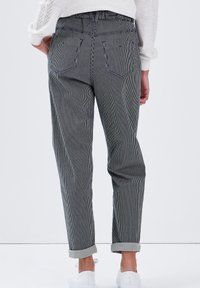 Randiga, högmidjade byxor i svart och vitt, med avslappnad passform, uppvikta fållar och bakfickor. Blandning av bomull med en mjuk textur.