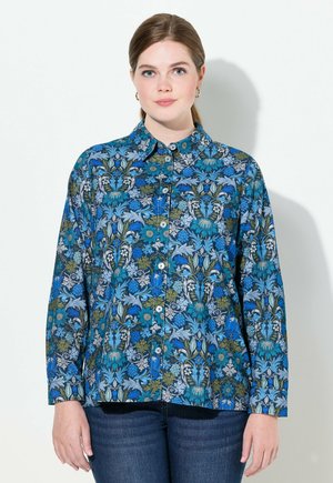 Camisa abotonada en un estampado floral multicolor, con tonos verdes y azules, mangas largas y un cuello clásico con un corte relajado.