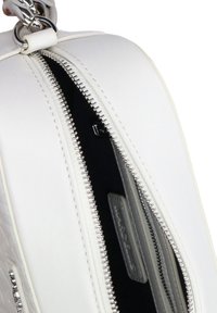 Witte leren tas met zilveren ritsdetails, gladde textuur en hoekig ontwerp. Binnenzijde heeft grijze stof met zichtbaar label.