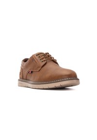 Zapatos de cuero marrón con cordones, punta redondeada, suela beige y costuras decorativas. Presenta un pequeño logo y un detalle cerca del talón.