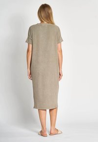 Langes, olivgrünes Kleid mit kurzen Ärmeln, lockerem Sitz und glatter Textur; verfügt über einen rundhalsausschnitt und seitliche Schlitze am Saum.