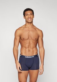 Navy blue cotton boxer briefs with an elastic waistband featuring white Adidas logo and three stripes design. Fitted shape, smooth texture.