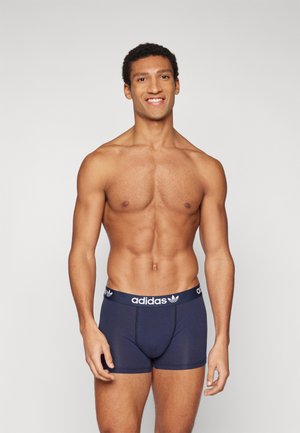 Sötétkék pamut boxer alsónadrág elasztikus derékpánttal, fehér Adidas logóval és három csíkos dizájnnal. Formázott fazon, sima textúra.