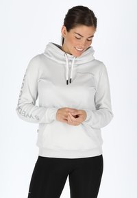 Hoodie grigio chiaro con colletto alto, lacci regolabili e tasche laterali. Presenta la scritta "SWEDEMOUNT" stampata sulla manica sinistra. Materiale morbido.