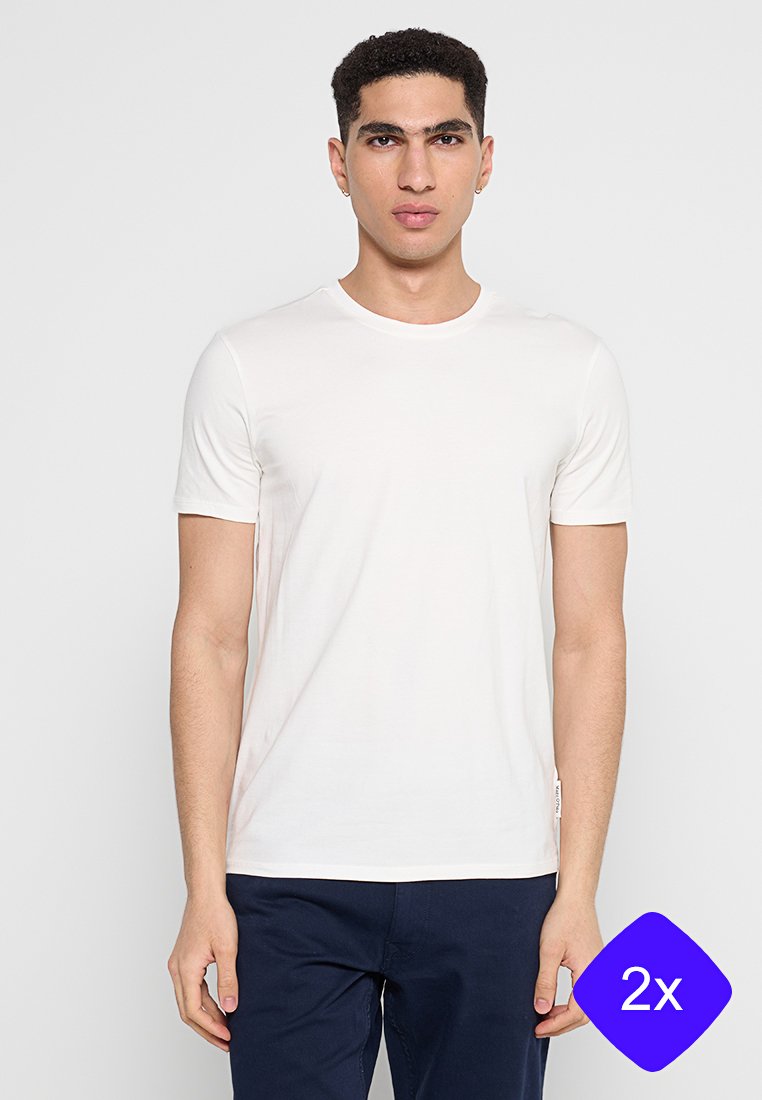 Weißes T-Shirt mit kurzen Ärmeln und Rundhalsausschnitt, aus weichem Stoff gefertigt. Sauberes, minimalistisches Design mit einem Etikett an der Seite. Getragen mit dunkelblauer Hose.