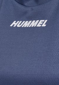 Tejido deportivo azul marino con un patrón texturizado; destacado logo blanco "HUMMEL" en una posición prominente.