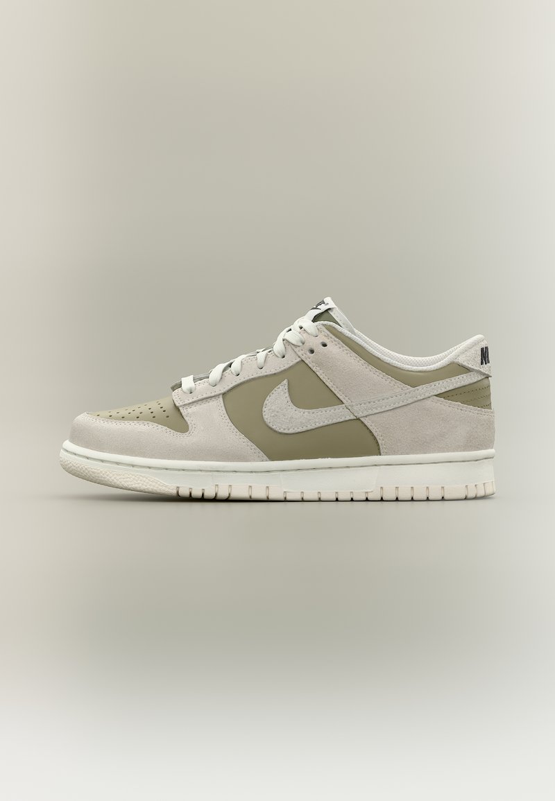 Χαμηλό παπούτσι Nike σε μπεζ και εκρού σουέντ με λευκά κορδόνια και λευκή σόλα, εμφανίζεται από το πλάι σε ουδέτερο φόντο.