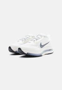 White Nike running shoes with mesh material, reflective laces, a cushioned sole, and a grey swoosh logo on the side. Textured black outsole.