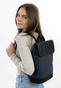 Sac à dos noir et bleu marine avec un design à rabat, fabriqué en matériau texturé, doté de bretelles réglables et d'une poignée supérieure.