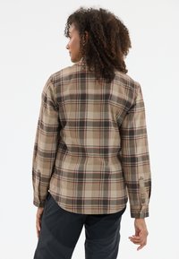 Bruin en beige geruit flanellen shirt met lange mouwen, knoopmanchetten en een afgeronde onderkant. De stof heeft een zachte textuur en zichtbare stiksels.