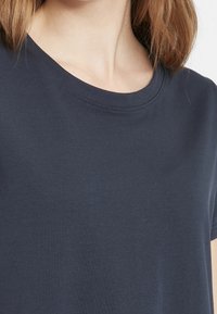 Tmavě modré tričko vyrobené z měkké bavlny, s kulatým výstřihem, krátkými rukávy a hladkým povrchem bez viditelných vzorů nebo akcentů.