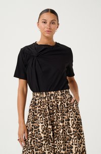 T-shirt noir avec un design noué à l'avant, associé à une jupe imprimée léopard arrivant aux genoux, dotée d'une taille élastique et de poches latérales.