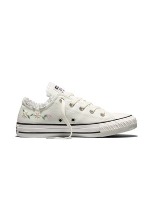Weißer niedriger Canvas-Sneaker mit Spitzenbesatz, Blumenstickerei an der Ferse, weißen Schnürsenkeln und schwarzer gestreifter Gummisohle.