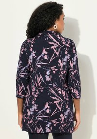 Tunic a stampa floreale blu navy, con fiori rosa e viola. Maniche a tre quarti, taglio dritto, tessuto morbido con una leggera elasticità.