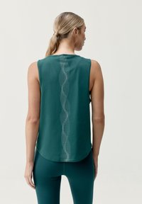 Top atletico senza maniche color verde acqua con orlo arrotondato, caratterizzato da un motivo verticale texturizzato lungo il centro della schiena. Tessuto liscio e traspirante.