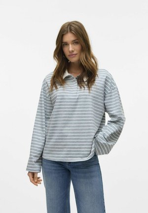 Polo à manches longues rayé gris et blanc avec col et fentes sur les côtés, associé à un jean bleu clair. Tissu doux avec une coupe décontractée.
