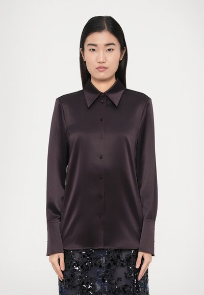 Chemise boutonnée en satin violet foncé avec un col classique, des manches longues et une texture lisse, associée à une jupe à sequins.