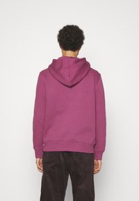 Felpa con cappuccio viola dotata di tasca a marsupio, polsini e orlo a costine, realizzata in morbido tessuto misto cotone. La vista posteriore mostra il cappuccio.