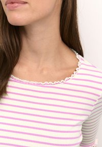 Lilla og hvid stribet ribbet top med en bølget udskæring. Stoffet har en blød tekstur og en tætsiddende design, der fremhæver skuldrene.
