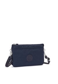 Marinblå nylon crossbody-väska med en slät yta, dragkedja och en rund logobadge. Har en justerbar rem och metallbeslag.
