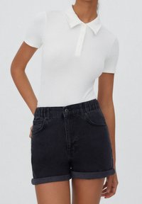 Polo bianco a costine con colletto e patta dei bottoni abbinato a pantaloni corti in denim scuro, con orlo arrotolato e vita elastica.