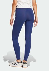 Marinblå leggings i stretchig kvalitet, figurnära design, hög midja och slät yta. Avslappnade skor med svart- och vitdetaljer.