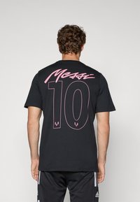 Sort bomulds T-shirt med korte ærmer. Har "Messi" i pink kursiv og "10" i stor pink skrift på ryggen.