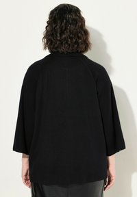 Maglione nero, dalla vestibilità ampia, con colletto e maniche a tre quarti. Tessuto morbido, design minimal e scende sotto la vita.