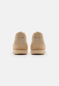 Beige velúr platform sportcipők kerek hátsó részel és sima gumitalppal. Textúrált felület és rétegezett középtalpi rész világosbarna díszítéssel.