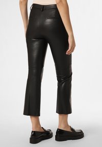 Black leather cropped pants with a fitted silhouette, featuring minimal stitching and discreet back pockets. Smooth texture and sleek design.