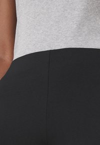 Szary prążkowany materiał u góry przechodzi w gładką czarną tkaninę poniżej, prezentując dopasowany, dwukolorowy projekt z czystymi liniami.